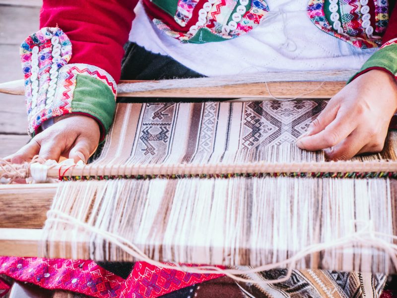 Artisan woman weaving fabric at Mundo Alpaca